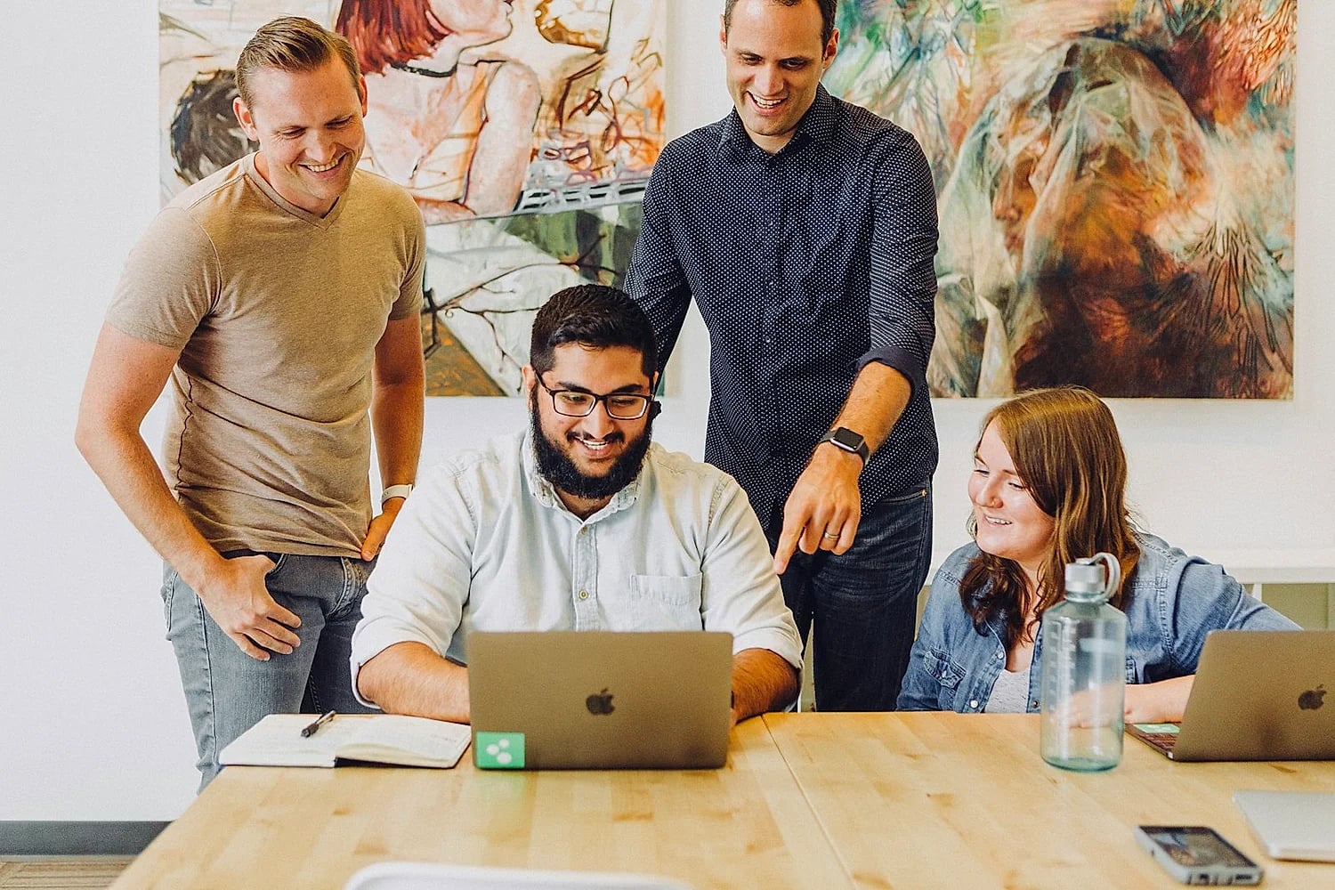 The MRZ team collaborating around a laptop in a bright, modern UAE office