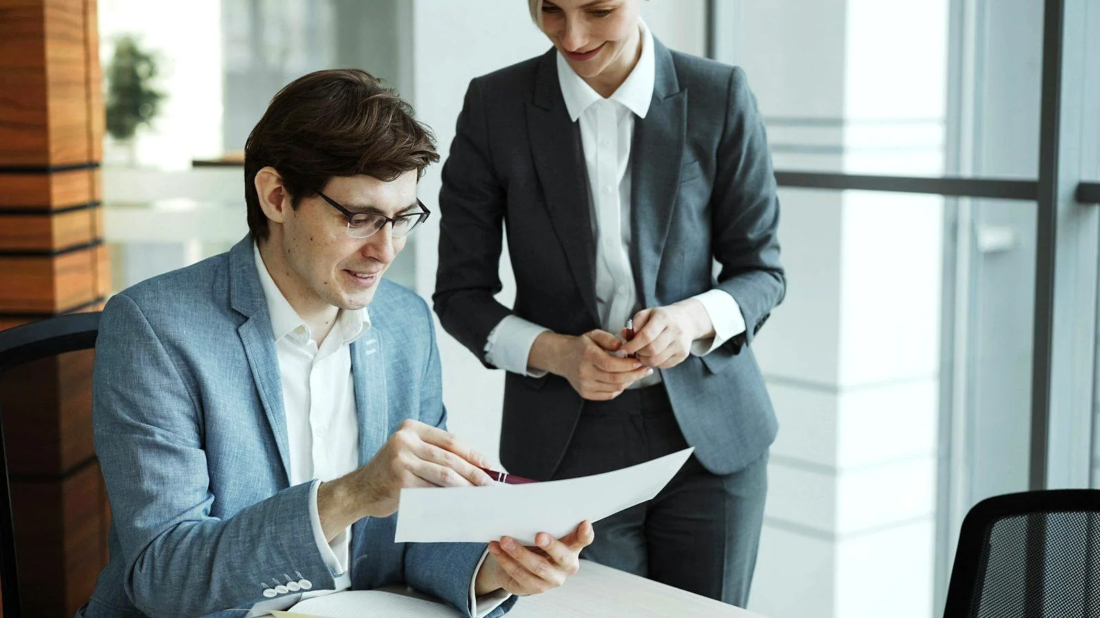 Two business partners reviewing a document together in a bright modern office