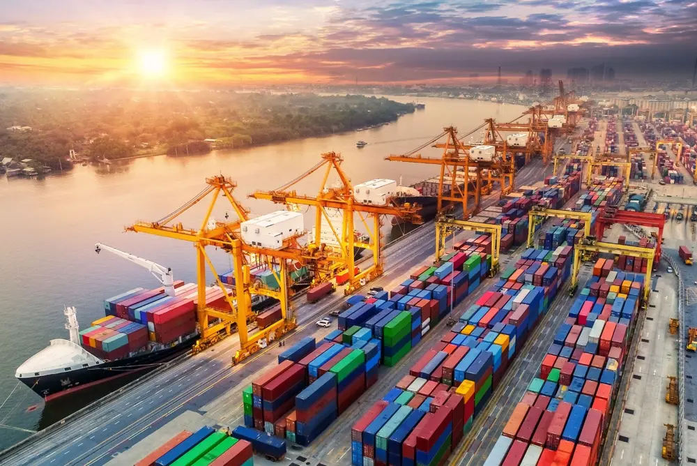 Aerial view of a container port at sunset, with gantry cranes loading a cargo ship