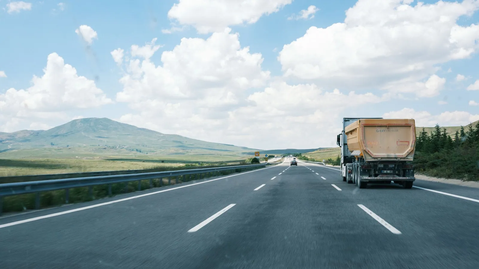 Cargo truck travelling along an open highway beneath a bright blue sky