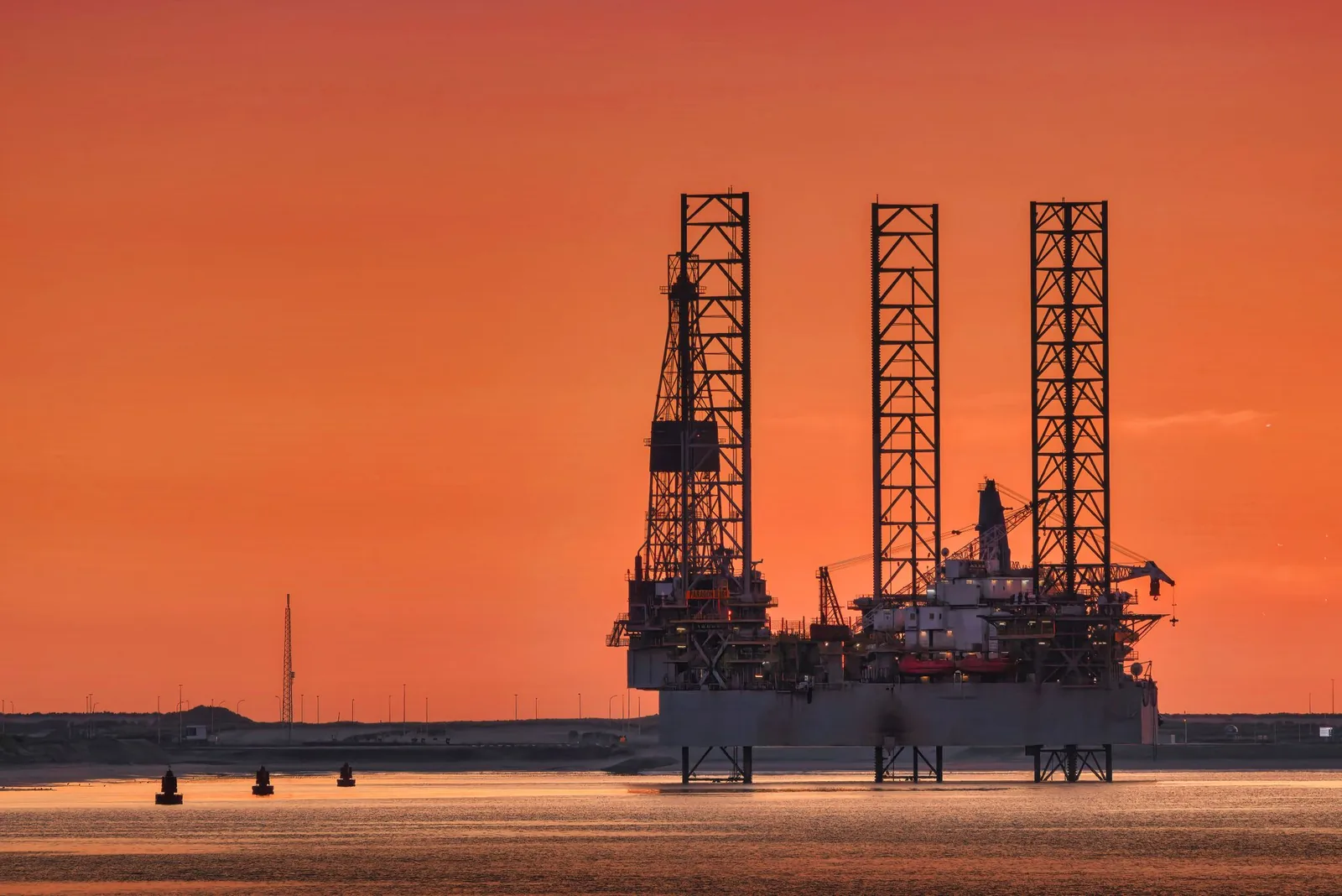 Offshore oil platform silhouetted against a sunset sky