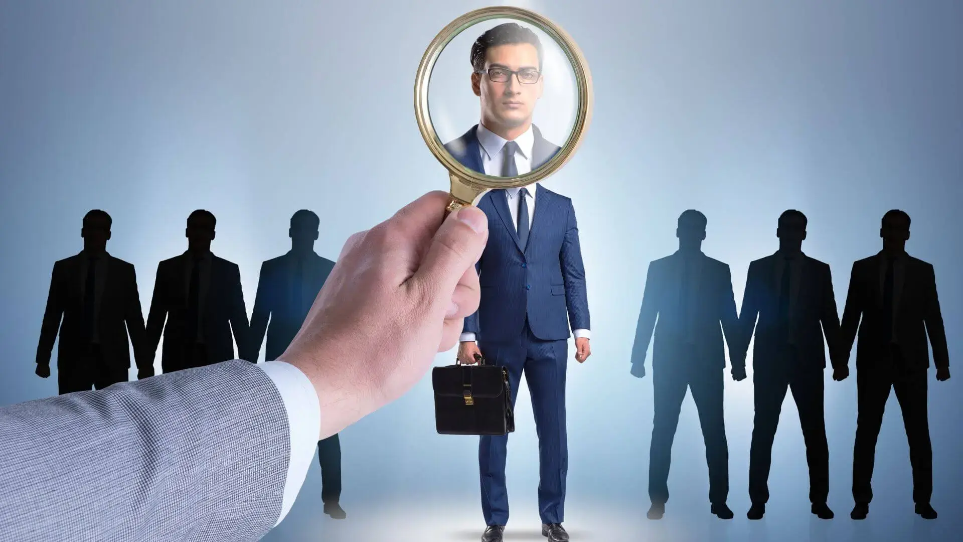 Magnifying glass singling out one candidate from a line of business silhouettes