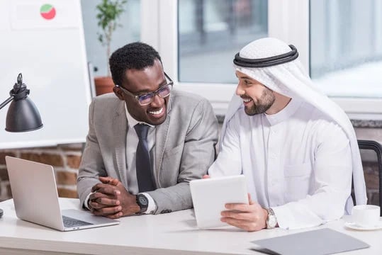 Two executives in an upbeat discussion over a tablet in a modern office